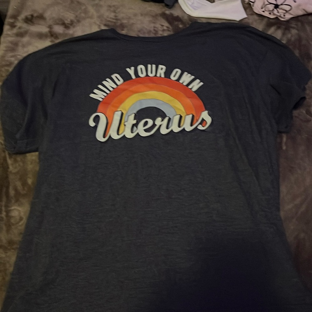 Dark gray T-shirt that says mine, your own uterus with a rainbow